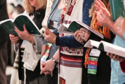 Closeup of a row of people standing with open prayer books and wearing prayer shawls 