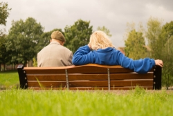 Seen from behind: older man and woman sitting on a bench 