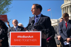 Rabbi Jonah Pesner speaking at a podium with the sign "NO BAN ACT"