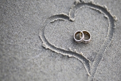 Heart drawn in sand with two rings inside