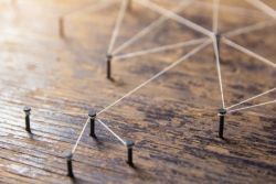 Pegs in a wooden board connected by white thread
