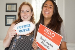 Two smiling teen girls holding signs that say FUTURE VOTER and SOCIAL JUSTICE ADVOCATE