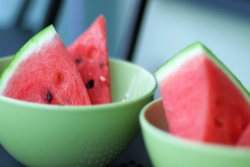 Slices of watermelon in green bowls on a wooden table