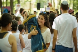 Young woman carrying a Torah scroll through the congregation at camp