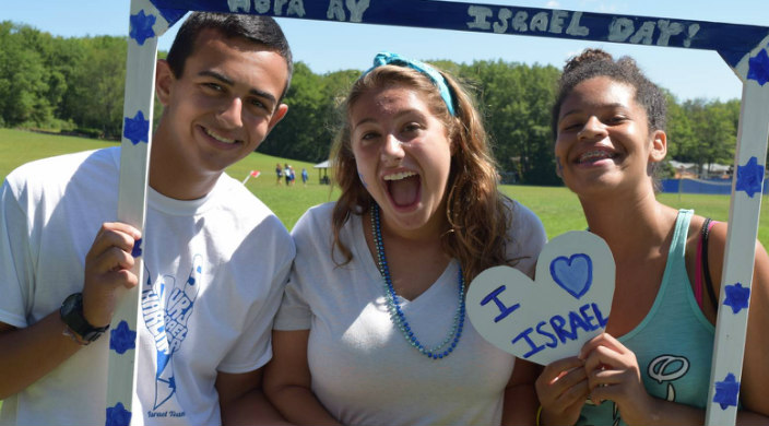 Three smiling teens holding I LOVE ISRAEL signs 