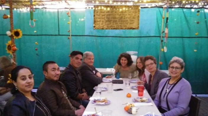 Group of people sitting at a table inside a sukkah