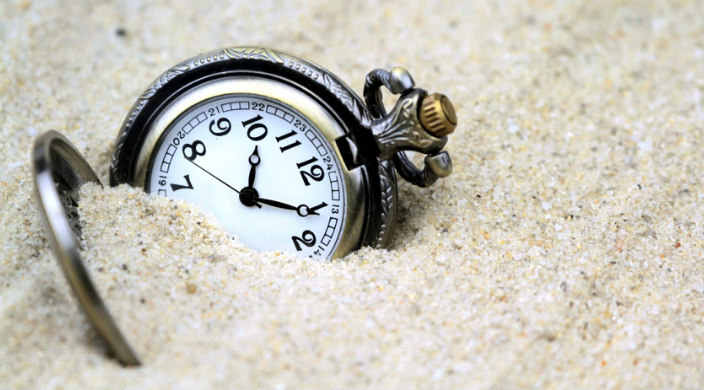 Timepiece partially buried in sand